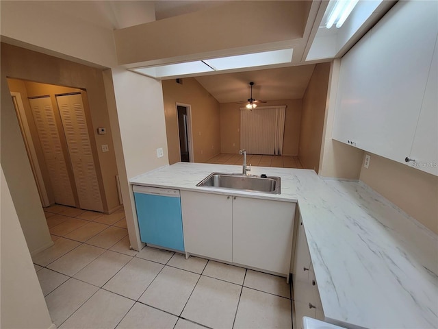 kitchen with light tile patterned flooring, a sink, white cabinetry, dishwasher, and lofted ceiling with skylight