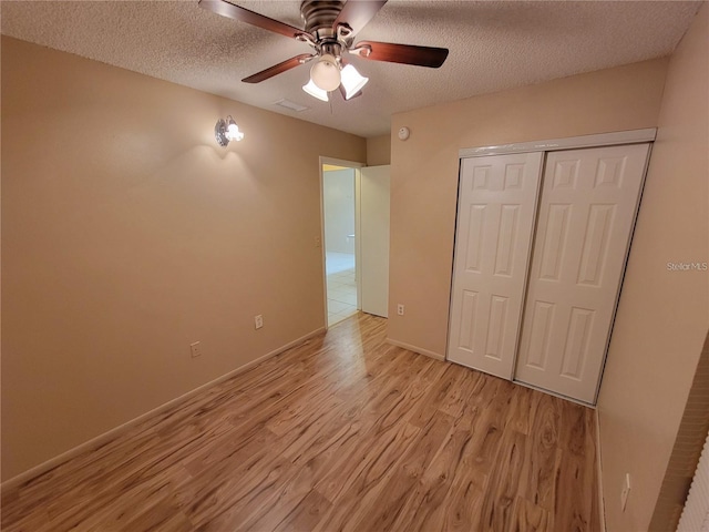 unfurnished bedroom featuring a closet, visible vents, light wood-style flooring, and a textured ceiling