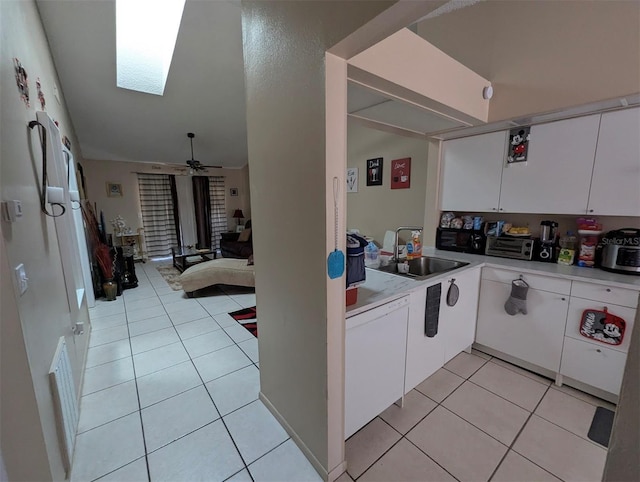 kitchen featuring light tile patterned floors, white cabinets, dishwasher, light countertops, and a sink