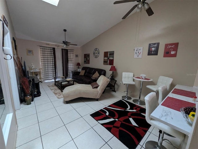 living room with light tile patterned floors, vaulted ceiling with skylight, and a ceiling fan