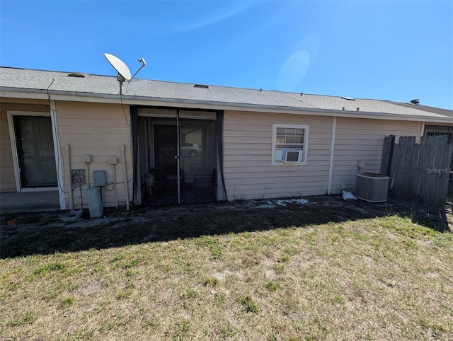 rear view of house with a lawn, fence, and central AC unit