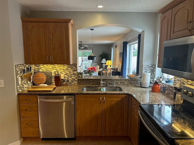 kitchen featuring dark stone counters, appliances with stainless steel finishes, a sink, and a healthy amount of sunlight