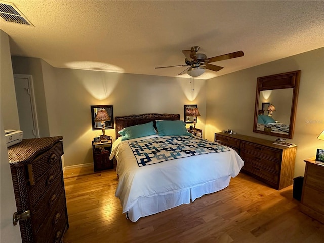 bedroom with a textured ceiling, ceiling fan, visible vents, and light wood-style floors