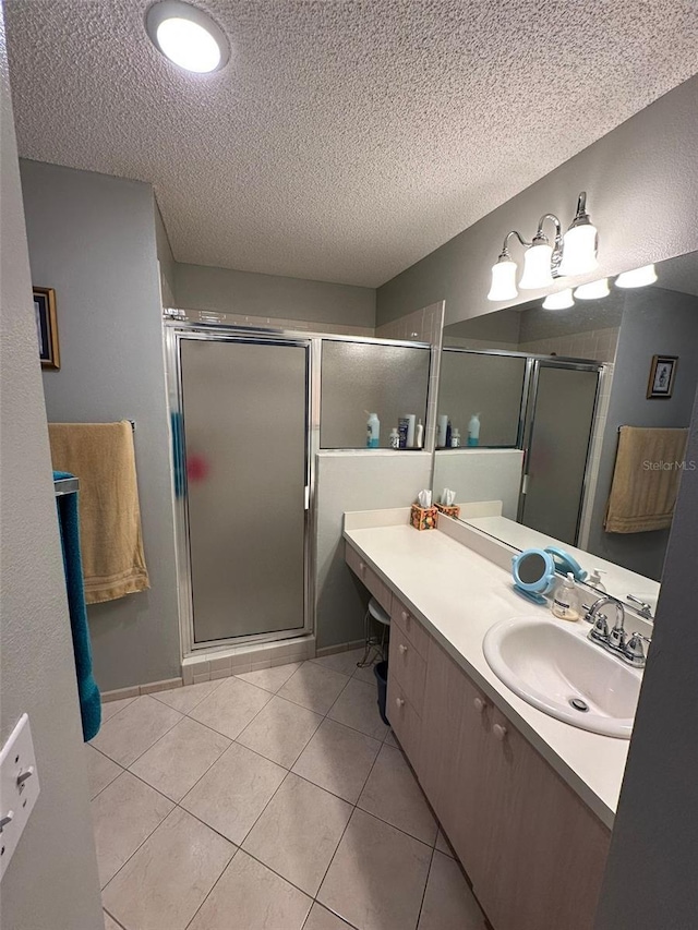 full bathroom featuring a stall shower, vanity, a textured ceiling, and tile patterned floors