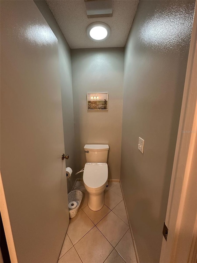 bathroom featuring a textured ceiling, tile patterned flooring, and toilet