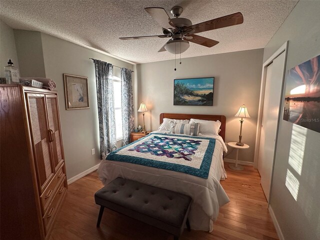 bedroom with light wood-type flooring, ceiling fan, a textured ceiling, and baseboards