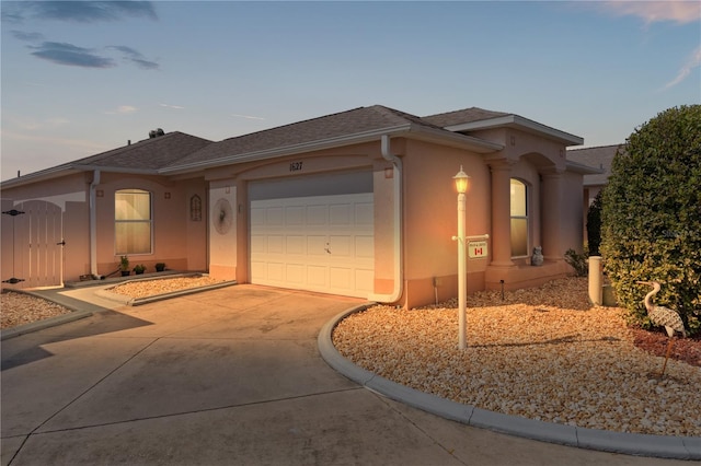 ranch-style house with concrete driveway, roof with shingles, an attached garage, and stucco siding