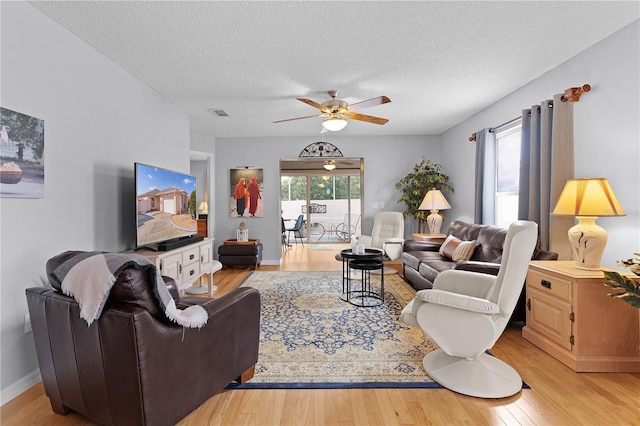 living area featuring ceiling fan, a textured ceiling, baseboards, and wood finished floors