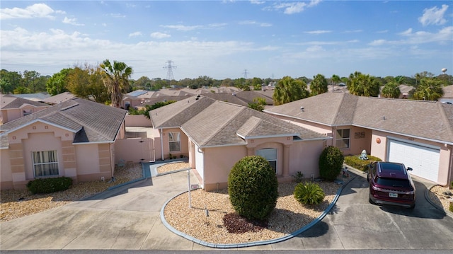 view of front facade with a residential view, concrete driveway, an attached garage, and stucco siding