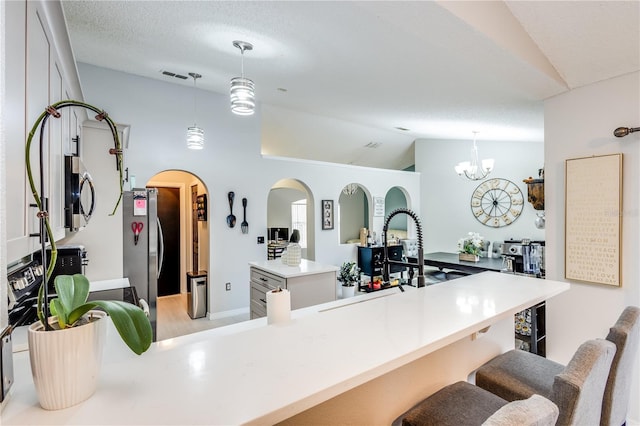 kitchen with stainless steel appliances, lofted ceiling, visible vents, a kitchen island, and a kitchen bar