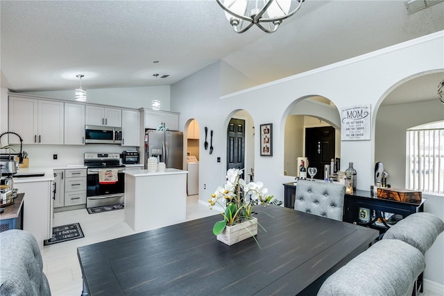 dining area with light wood finished floors, lofted ceiling, visible vents, a textured ceiling, and washer / dryer