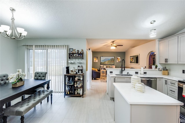 kitchen with a center island, a peninsula, a sink, light countertops, and stainless steel dishwasher