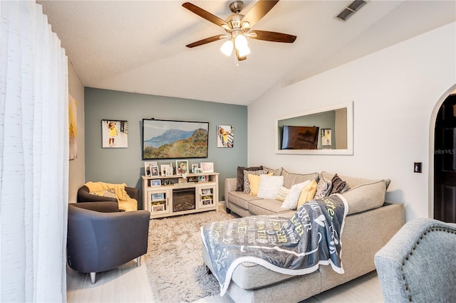 living room featuring arched walkways, visible vents, vaulted ceiling, and ceiling fan