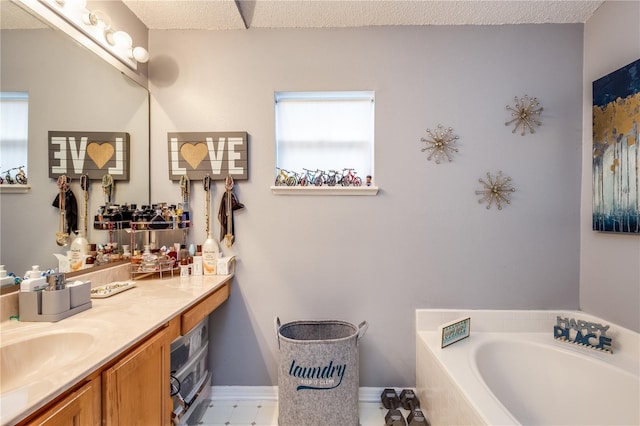 full bathroom featuring a textured ceiling, vanity, baseboards, and a bath