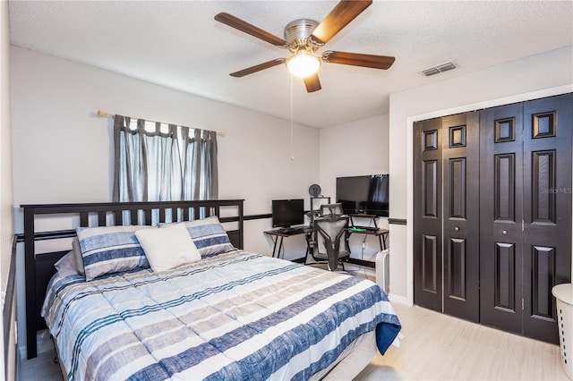 bedroom featuring a ceiling fan, a closet, visible vents, and a textured ceiling