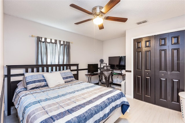 bedroom featuring a closet, visible vents, ceiling fan, and a textured ceiling