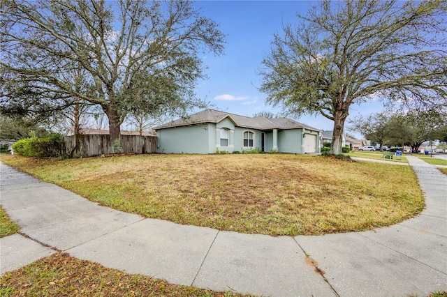 view of front facade with a garage, a front lawn, fence, and stucco siding