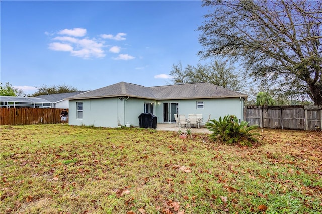 rear view of house with a yard, a patio area, fence, and stucco siding