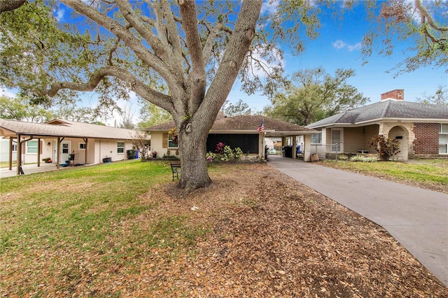 ranch-style home featuring a carport, a front yard, driveway, and a chimney