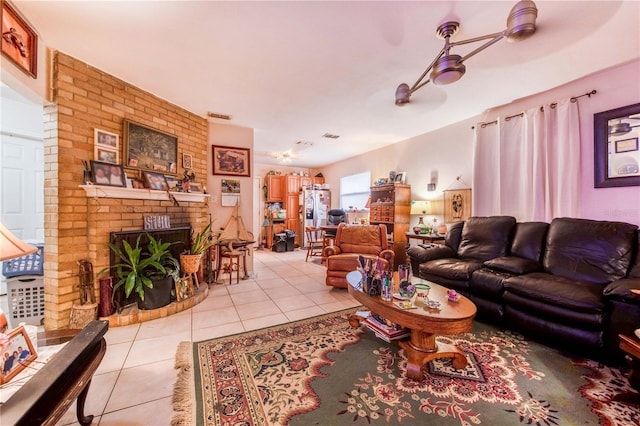 living area with a ceiling fan, a brick fireplace, and light tile patterned flooring