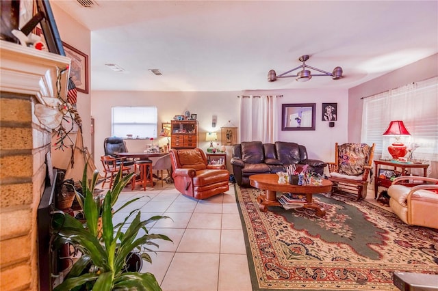 living area with a ceiling fan, visible vents, a fireplace, and light tile patterned floors