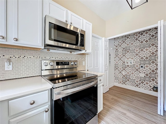 kitchen with light wood finished floors, stainless steel appliances, light countertops, white cabinets, and tasteful backsplash