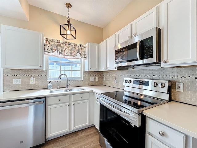 kitchen with white cabinets, appliances with stainless steel finishes, light countertops, and a sink