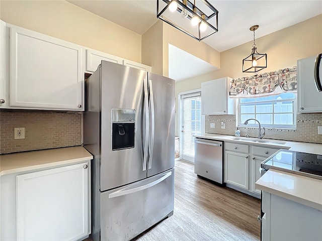 kitchen with a sink, light countertops, light wood-style floors, appliances with stainless steel finishes, and tasteful backsplash