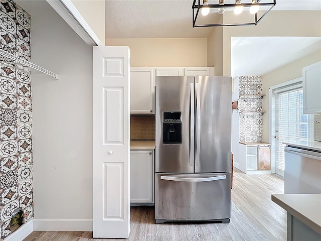 kitchen featuring baseboards, stainless steel appliances, light countertops, a textured ceiling, and light wood-type flooring