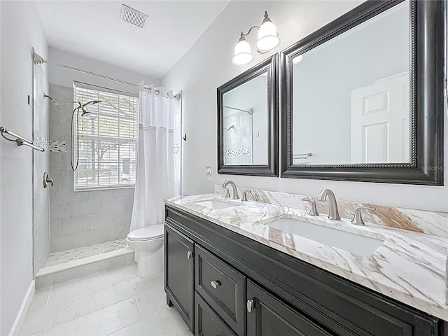 bathroom with double vanity, marble finish floor, tiled shower, and a sink