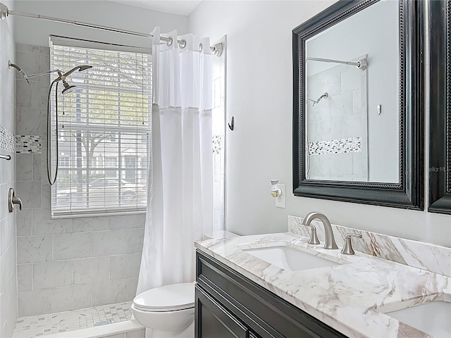 bathroom featuring toilet, vanity, and a tile shower