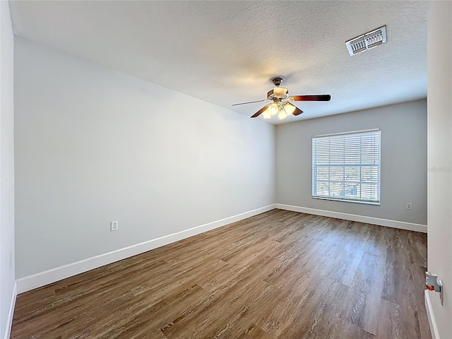 unfurnished room featuring visible vents, a textured ceiling, wood finished floors, baseboards, and ceiling fan