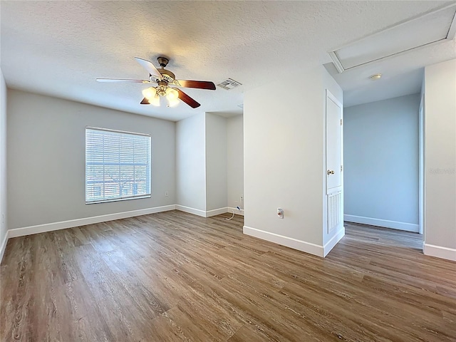 unfurnished room featuring a textured ceiling, wood finished floors, visible vents, and baseboards