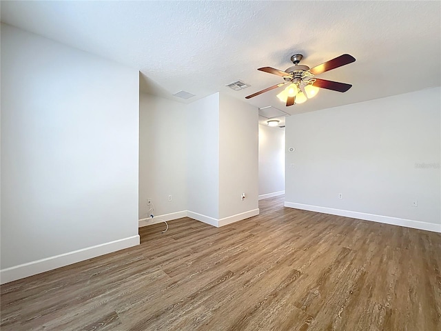 empty room featuring visible vents, a textured ceiling, baseboards, and wood finished floors