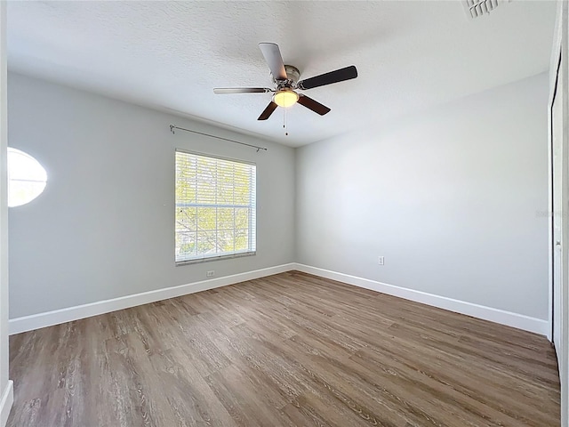 unfurnished room with visible vents, a textured ceiling, baseboards, and wood finished floors