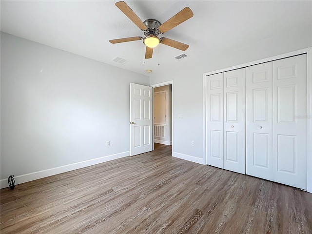 unfurnished bedroom with wood finished floors, baseboards, and visible vents