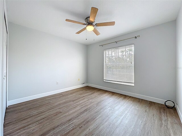 spare room featuring a ceiling fan, baseboards, and wood finished floors