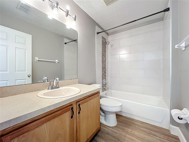 bathroom with wood finished floors, visible vents,  shower combination, a textured ceiling, and toilet