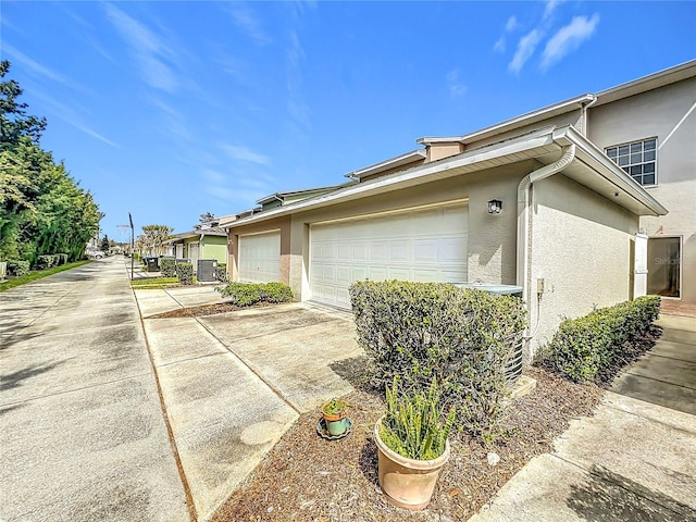 view of property exterior featuring stucco siding, driveway, and a garage