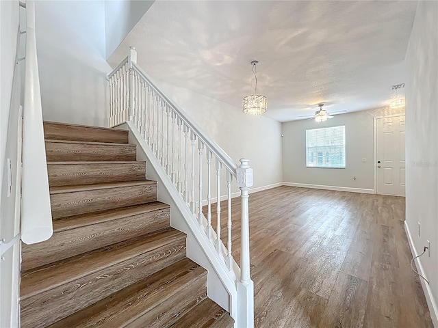 stairs featuring ceiling fan, visible vents, baseboards, and wood finished floors