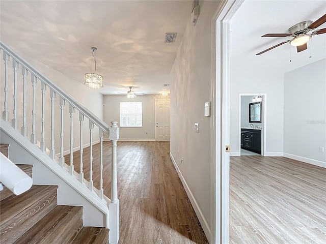 foyer entrance featuring visible vents, ceiling fan, baseboards, stairway, and wood finished floors