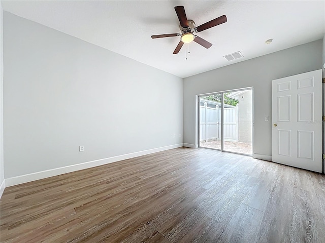 empty room with wood finished floors, baseboards, visible vents, and ceiling fan