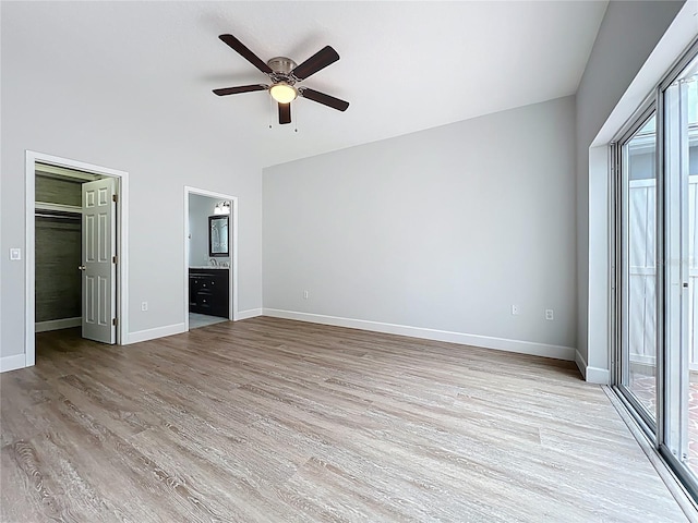 unfurnished bedroom featuring baseboards, ensuite bath, ceiling fan, a spacious closet, and light wood-type flooring