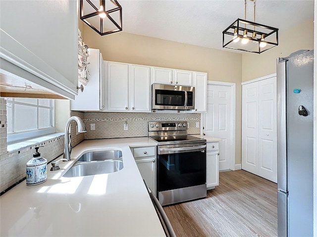 kitchen with a sink, white cabinetry, stainless steel appliances, light countertops, and decorative backsplash