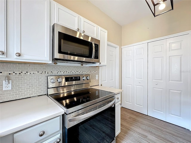 kitchen featuring light wood-type flooring, light countertops, decorative backsplash, white cabinets, and stainless steel appliances