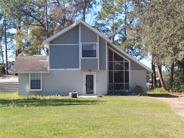 back of property with a yard and roof with shingles