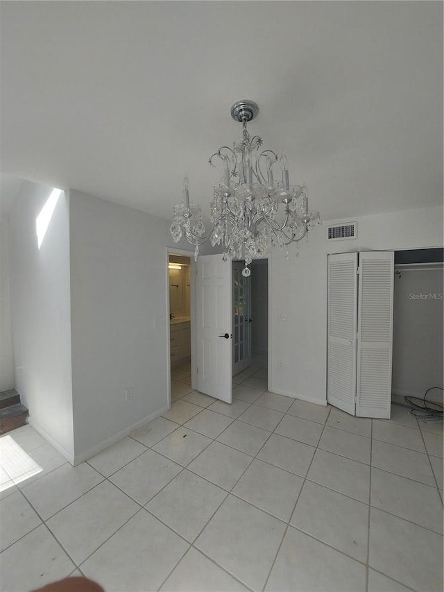 interior space with light tile patterned floors, a chandelier, visible vents, baseboards, and a closet