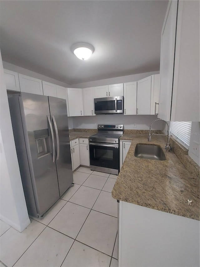 kitchen with white cabinets, stainless steel appliances, a sink, and light tile patterned flooring