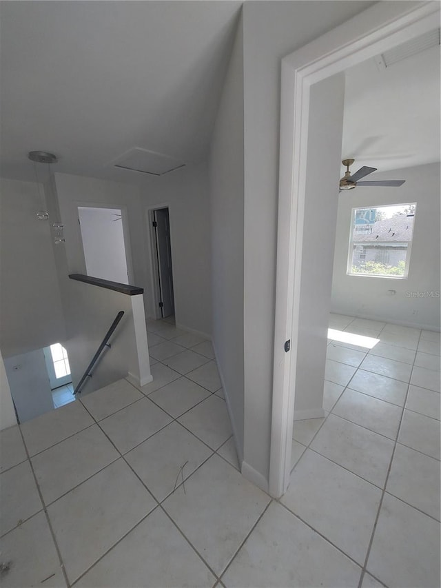 hallway with an upstairs landing and light tile patterned floors