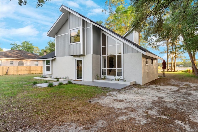 back of property featuring stucco siding, fence, a lawn, and a patio